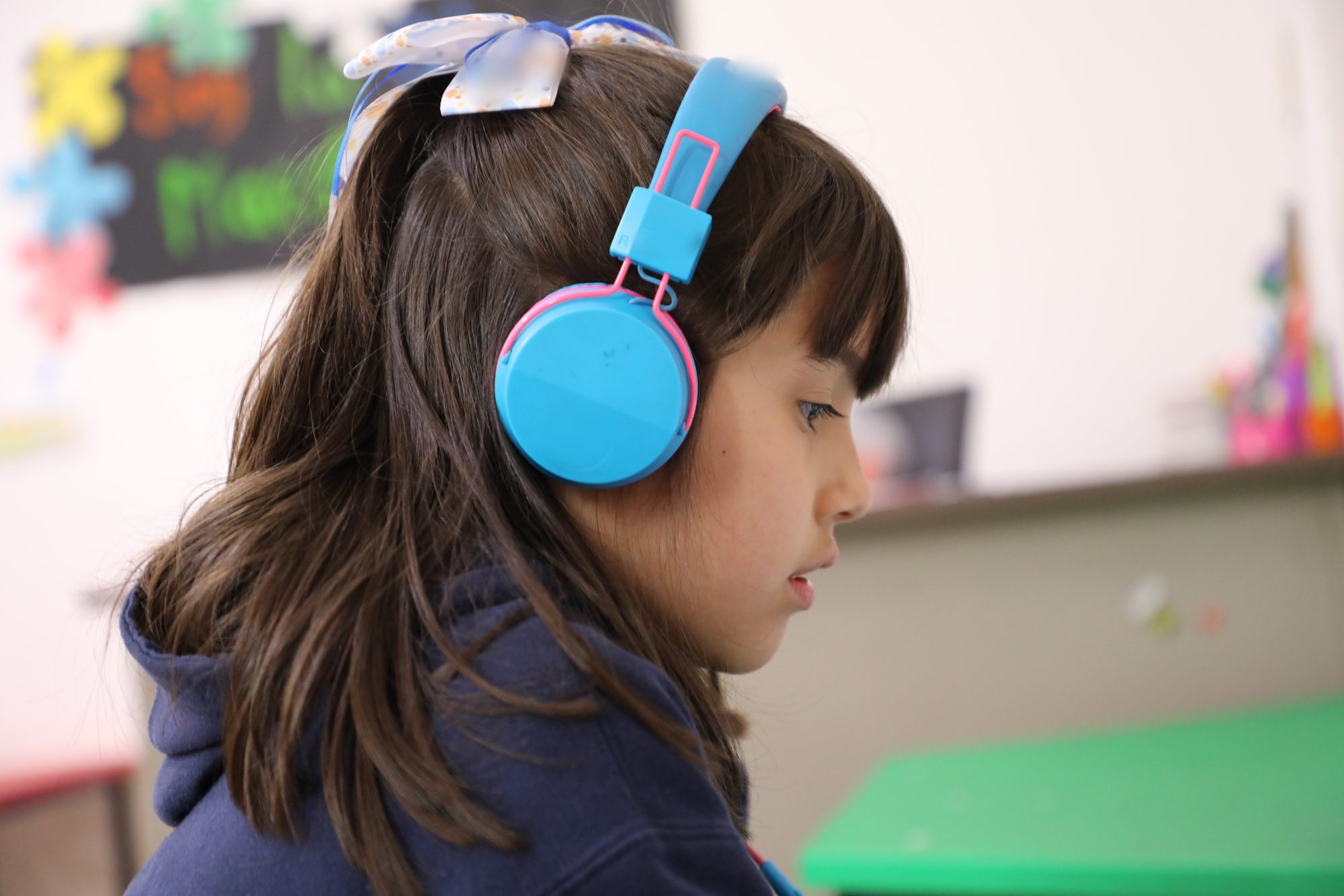 Una alumna de kínder del Instituto Zoe, con audífonos, atenta a su clase