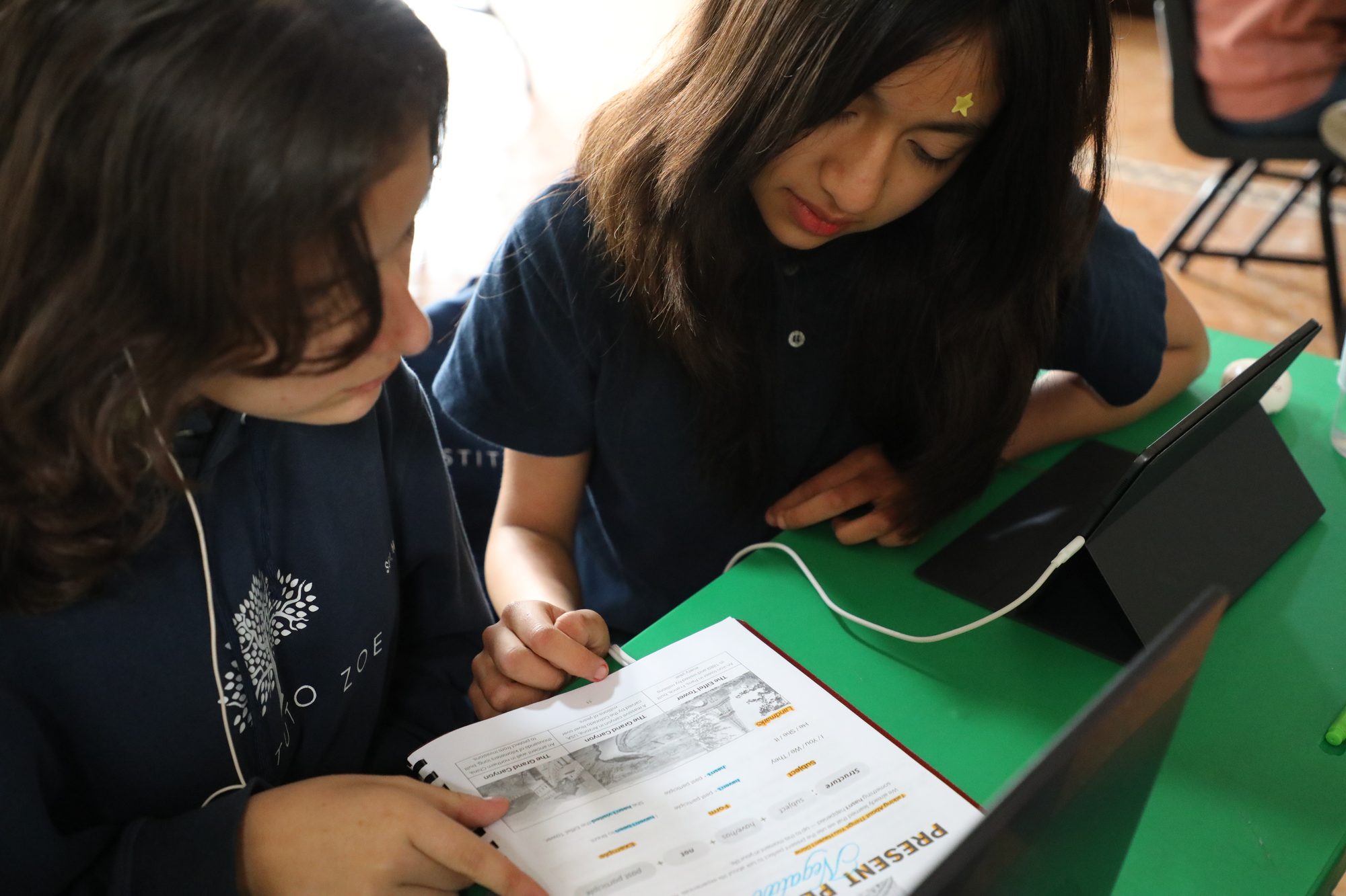 Dos alumnas de secundaria del Instituto Zoe revisan juntas su cuaderno de inglés