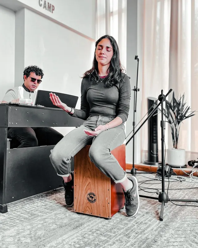 Joven toca el cajón junto al tecladista